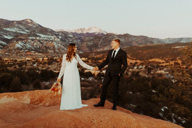 https://fetch.getnarrativeapp.com/static/ab5b47ae-6232-49c2-917c-e254d3eae149/Bride-and-groom-hold-hands-in-front-of-an-alpenglow-covered-Pikes-Peak-during-their-sunrise-elopement-in-Garden-of-the-Gods-in-Colorado-Springs.-.jpg?w=750